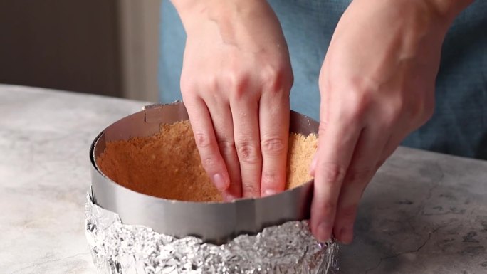 一名女子用饼干屑雕刻出蛋糕、芝士蛋糕、馅饼的边缘，一名女子将饼干屑压成芝士蛋糕的视频片段