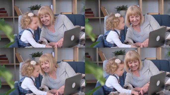 微笑的奶奶和小孙女一起用笔记本电脑看动画片。