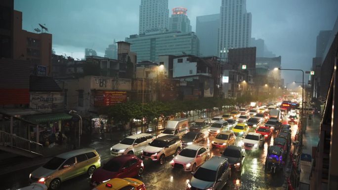 在一个雨夜，许多五颜六色的汽车在市中心的道路上堵塞。背景是高大的现代建筑和多云的天空