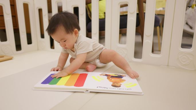 亚洲中国小孩宝宝坐在地垫上看触摸书绘本