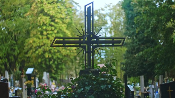 古老的金属十字架覆盖着基督的形象，矗立在市公墓的坟墓之间