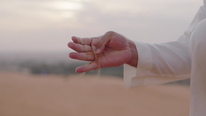 沙特人沙漠捧起沙子飘散在手中