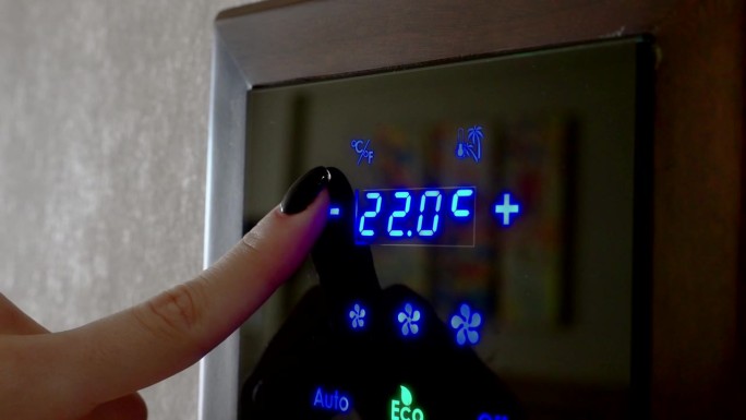视频4 k。女孩用手指在房间墙壁上的电子面板上设定空调的温度。现代室内气候控制系统