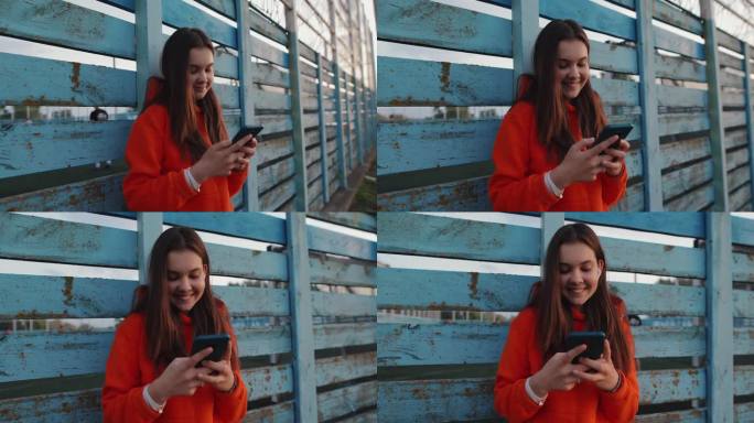 十几岁的女孩站在围栏附近玩智能手机