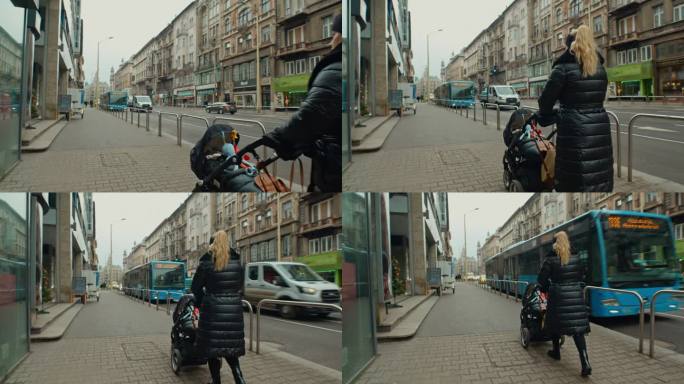 匈牙利布达佩斯市，一名身穿冬衣的女子推着婴儿车走在人行道上的后视图