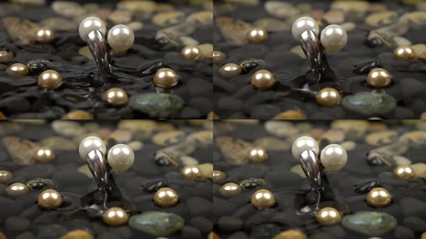水滴落在镶有珍珠的银戒指上，那是在水中的五颜六色的鹅卵石，慢动作