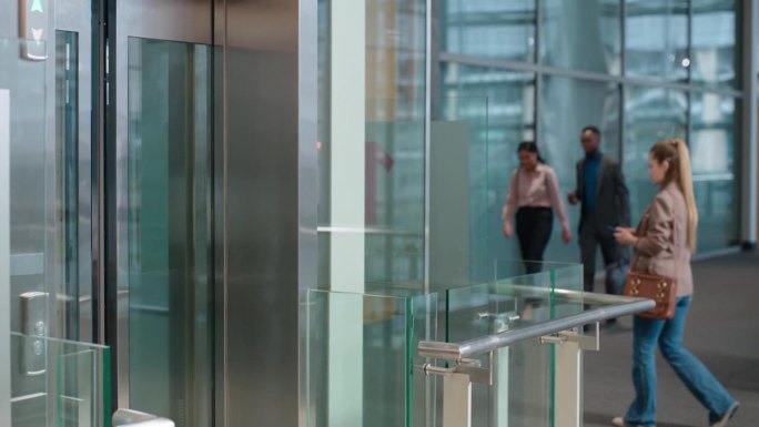 商务，男人和女人或从电梯出口走出来谈话，快乐和大厅在公司的工作场所。专业人士，在电梯门口与人沟通，讨