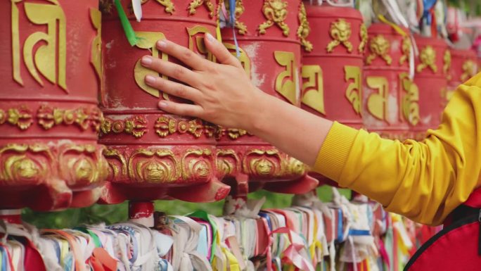 在佛教寺院，一位女朝圣者的手触摸着转动的经轮。佛塔寺庙里的经轮。佛教的宗教观念。