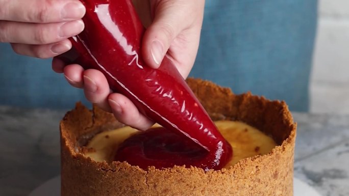 在厨房慢动作视频中，女性用手制作起司蛋糕，用草莓装饰香草起司蛋糕