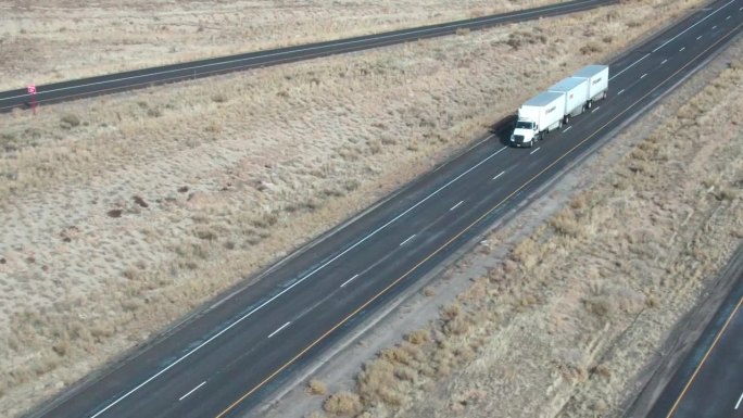 无人机拍摄了一辆白色半挂车和三个拖车在冬季下午在犹他州的I-70上向西行驶