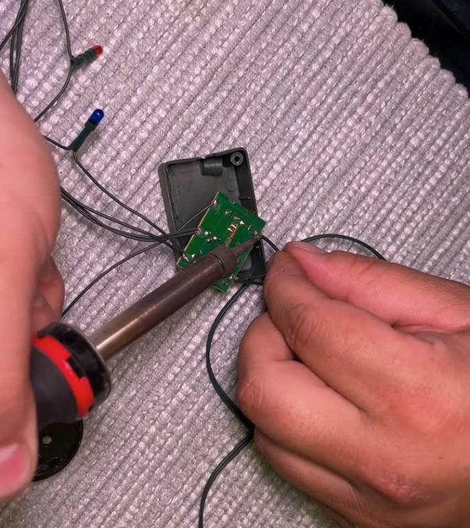 一个男人用电烙铁修理圣诞树。一个男人手拿电烙铁的特写。修理工在电环上焊接继电器。