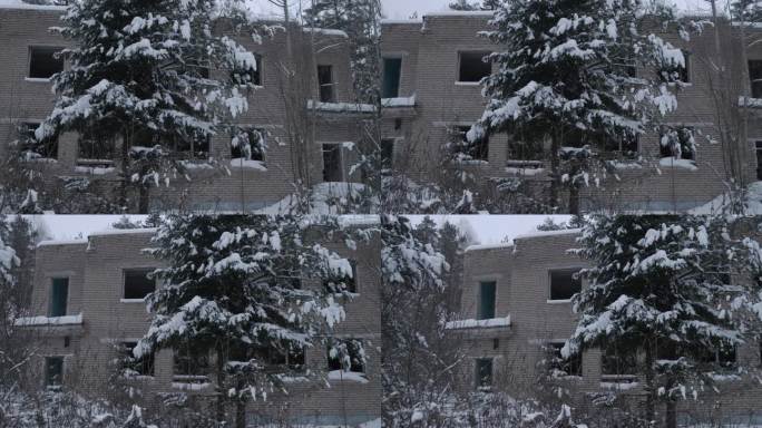 冬季森林中废弃的两层砖房，窗户破碎