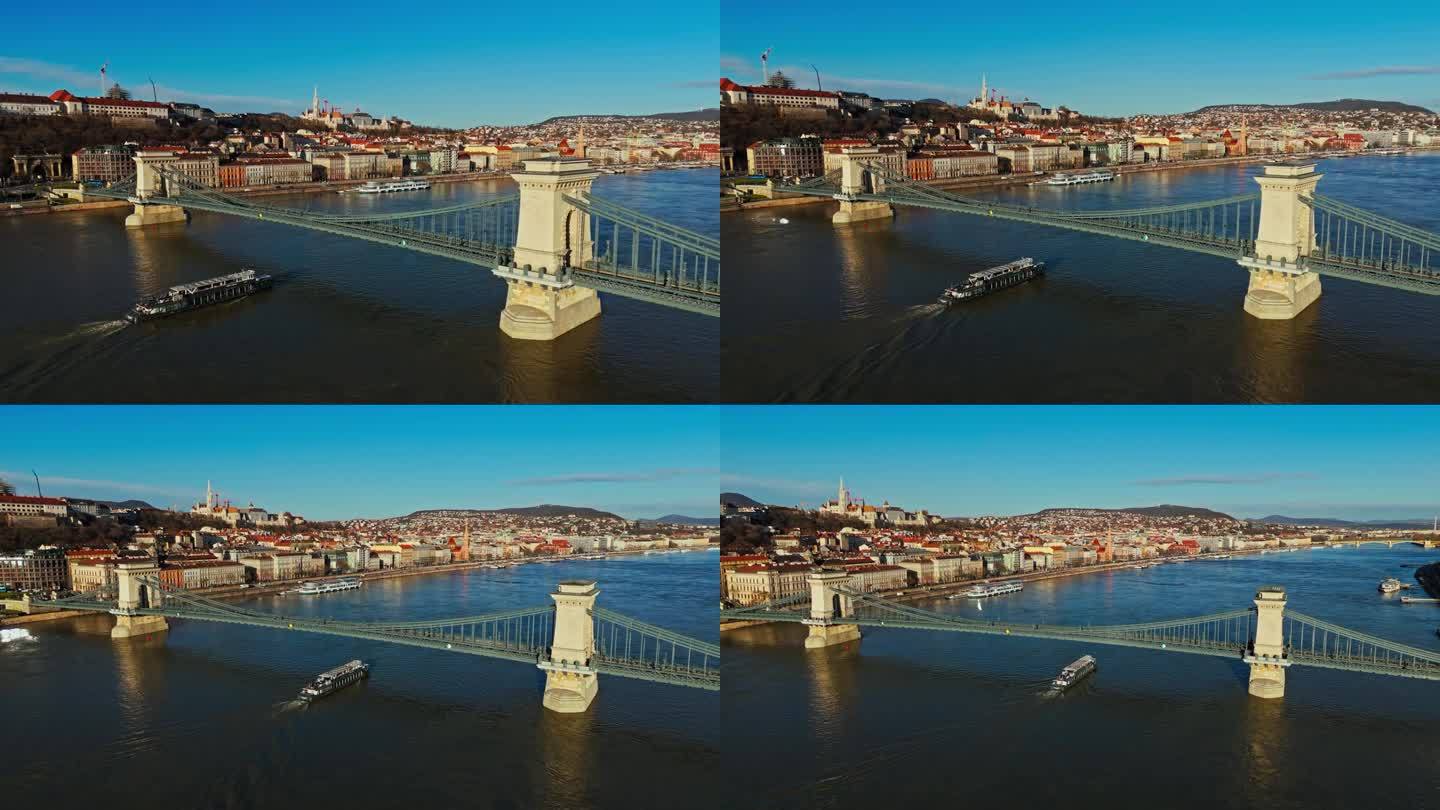 匈牙利布达佩斯，在晴朗的蓝天下，多瑙河Széchenyi链桥下渡船行驶的无人机镜头