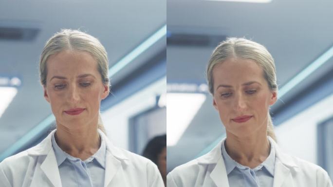 竖屏:一名身穿白大褂的女医生在医院走廊用平板电脑工作的画像。医疗保健专业人员或护士长看着镜头，温柔地