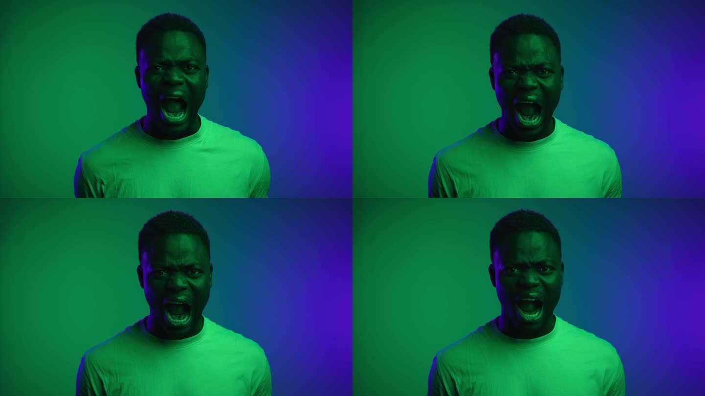 霓虹彩色镜头中黑人男子望着镜头尖叫的肖像。一个非裔美国人怒斥疯狂生活的消极生活方式。非洲人被痛苦和恐