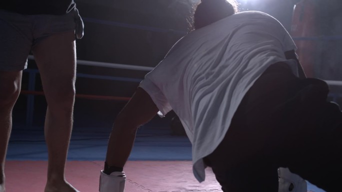 拳手被对手击败后从地板上爬起来，拳台内人站起来的韧性主题