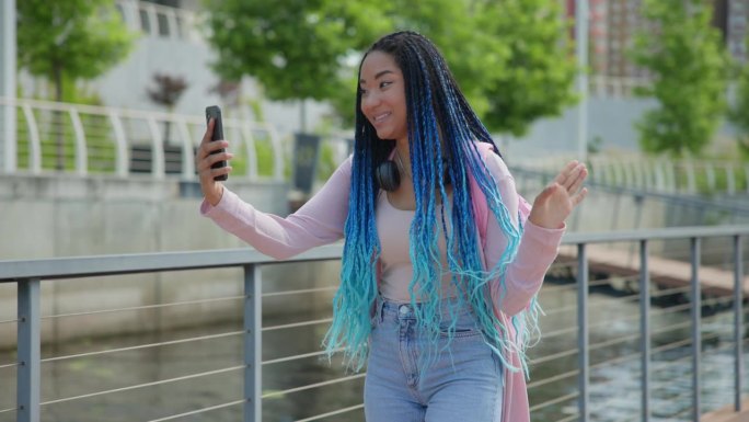 留着脏辫的年轻非裔美国女人在城市里走来走去打视频电话