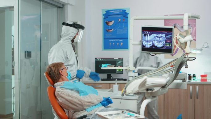 牙医全身穿著，显示病人的牙齿x光情况