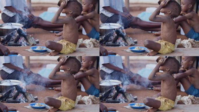 由于极度贫困、干旱和气候变化，贫穷、营养不良的非洲黑人儿童。从锅里喝水
