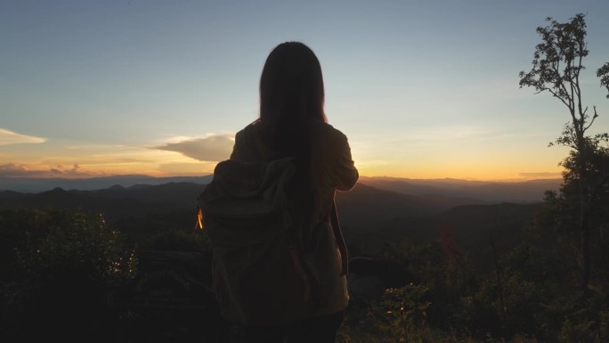 十几岁的女孩背着登山包，在山顶欣赏风景