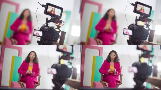 近距离拍摄一位穿着彩色衣服的女电视主持人:慢动作将焦点从相机转移到拍摄对象，热情的内容创作者为她的在