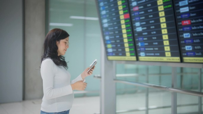 一名孕妇在机场的屏幕上查看登机时间