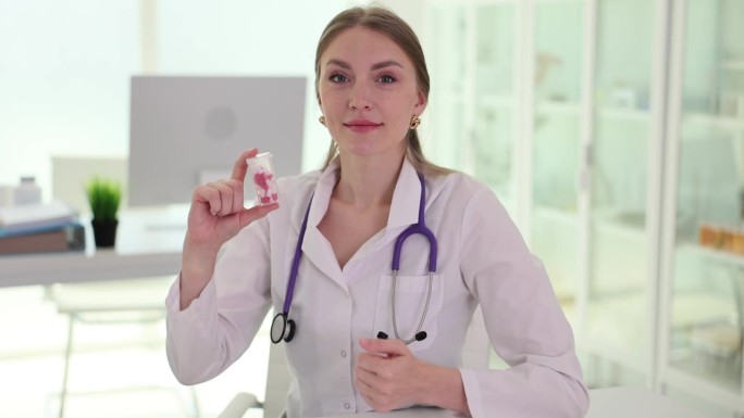 女家庭医生展示含有维生素的塑料药瓶