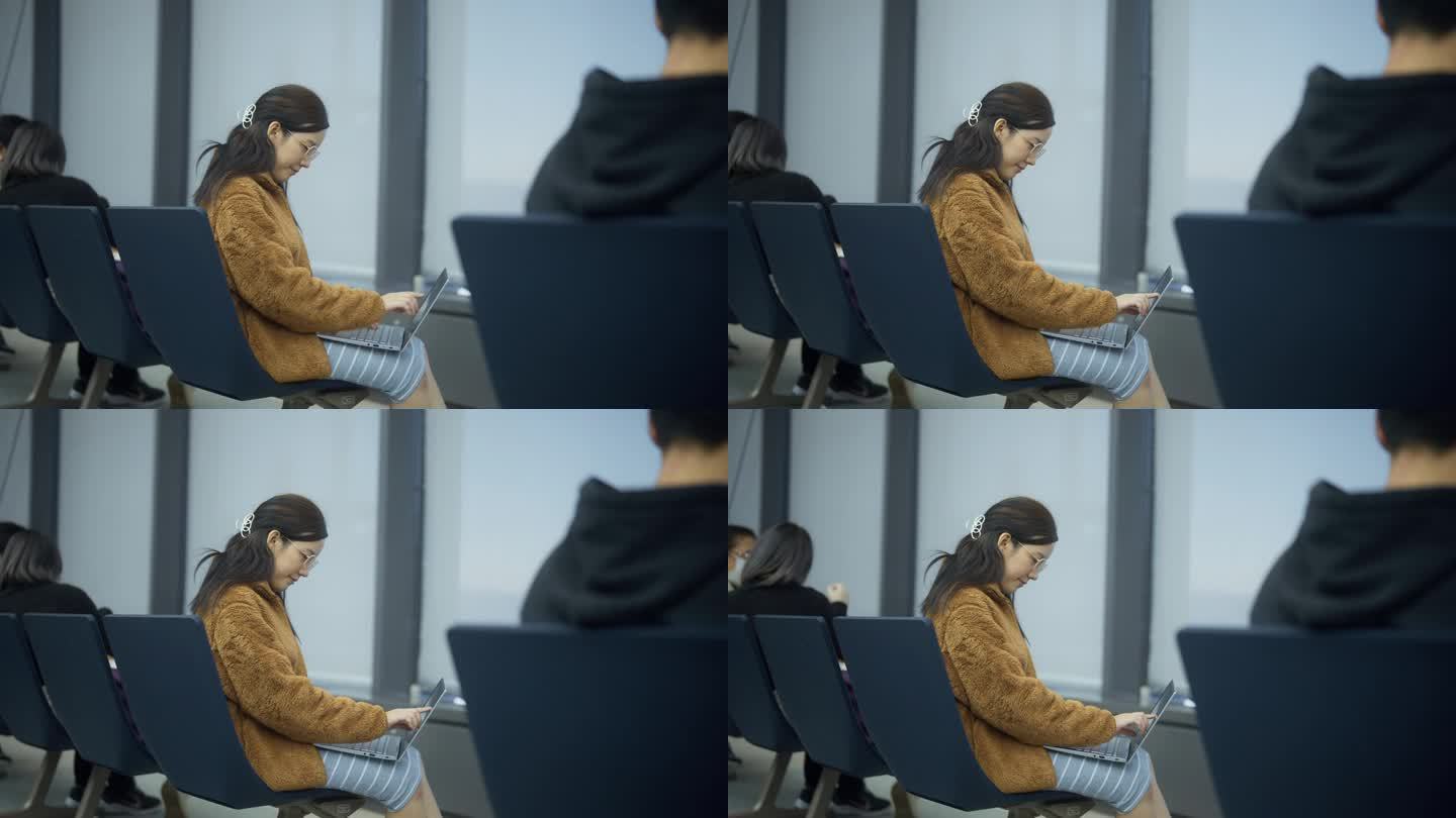 一个孕妇坐在机场用笔记本电脑工作