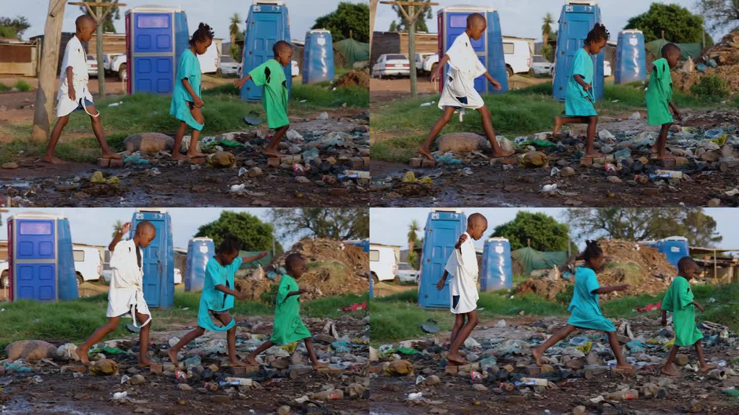 贫穷，三个贫穷的非洲黑人儿童在一个非正式定居点的移动厕所和臭气熏天的污水旁玩耍