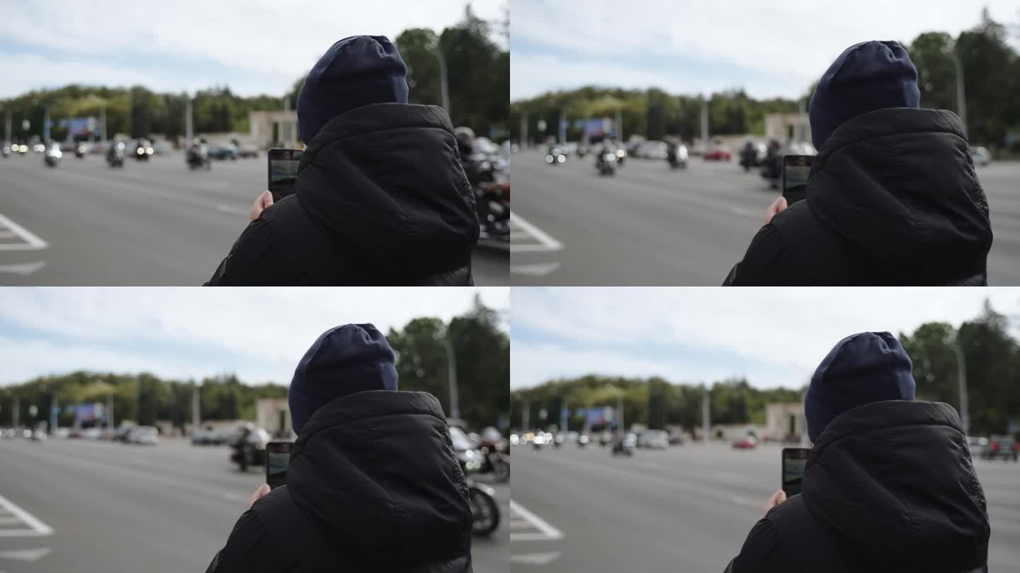 少年在电话中向城市摩托车队拍摄，背影。