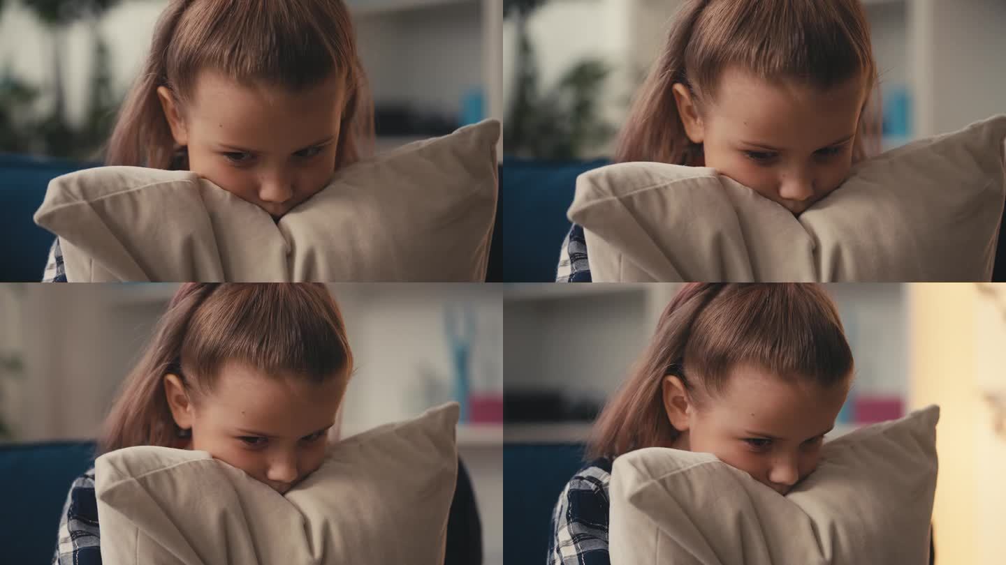 小女孩坐在沙发上感到不安，抱着枕头安慰