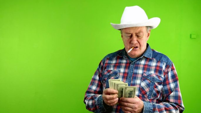 戴着白色牛仔帽的老人整理钞票，抽着烟，吹着烟。