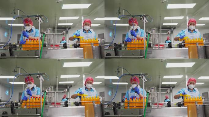 亚洲华人果汁工厂的工人在生产线上密封橙汁的瓶盖