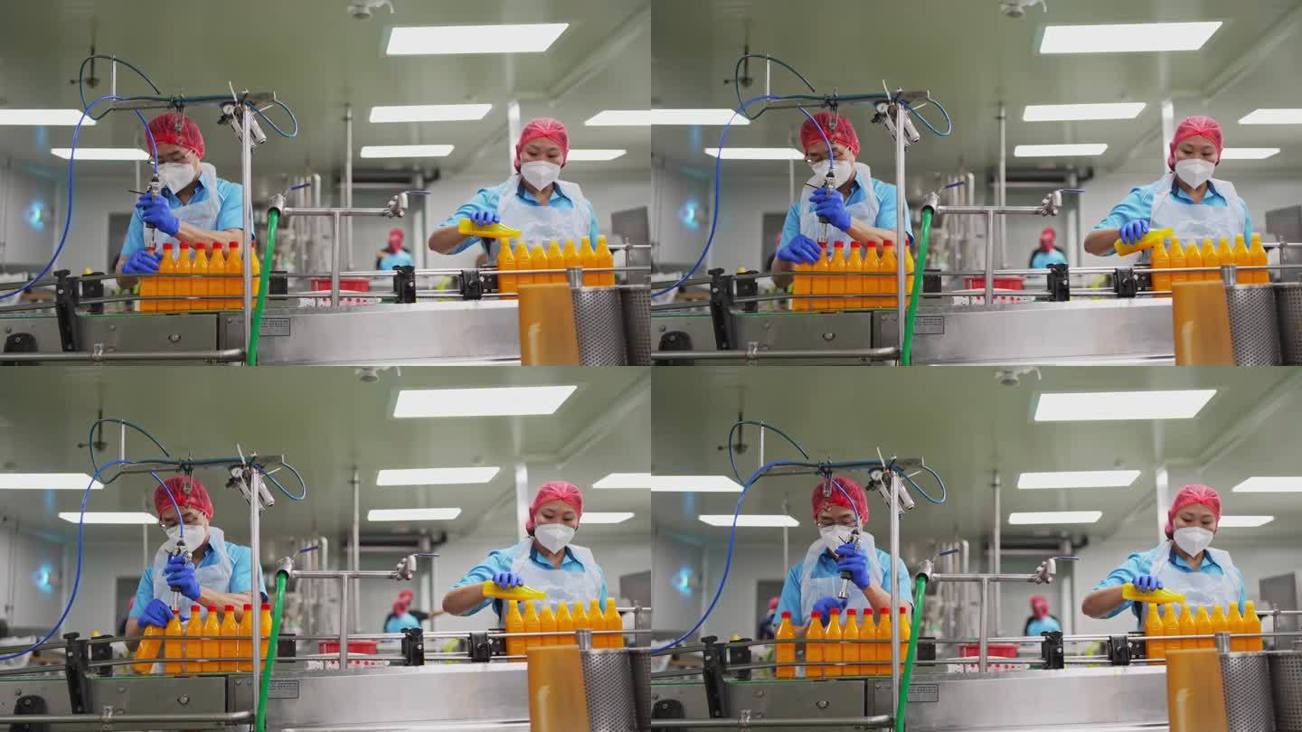 亚洲华人果汁工厂的工人在生产线上密封橙汁的瓶盖