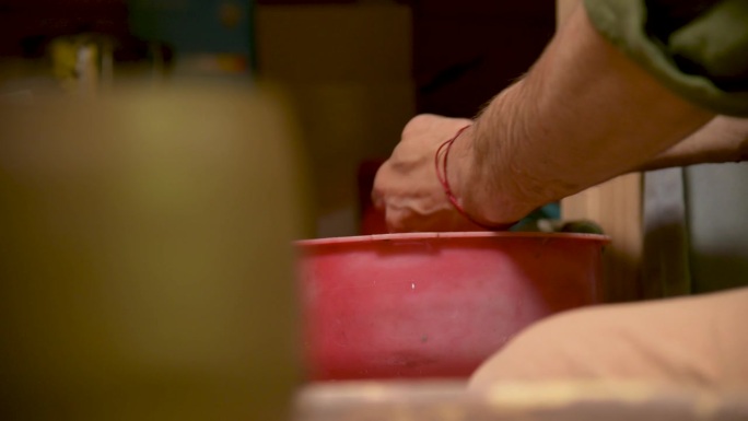 男陶工在制作完陶器后在红盆里洗手
