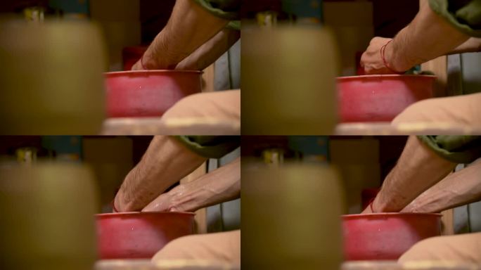 男陶工在制作完陶器后在红盆里洗手
