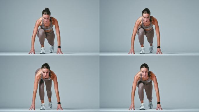 工作室肖像的女人在健身房健身服装开始短跑比赛对灰色背景