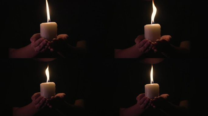 烛光指引生命，希望照亮，手握白烛的特写镜头，手握燃烧的白烛在黑暗中