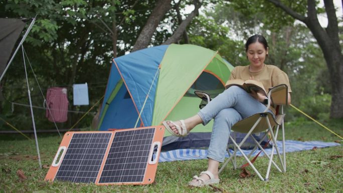 带着太阳能电池板野营的女人，可持续的生活理念