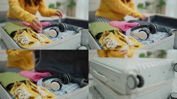 女旅客准备旅行，把衣服装进行李箱。旅行妇女把耳机和衣服装进旅行箱，准备度假旅行。旅游度假理念