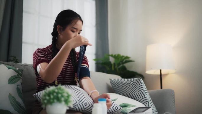 一名携带血糖传感器的亚洲少女正在家中使用数字血压仪