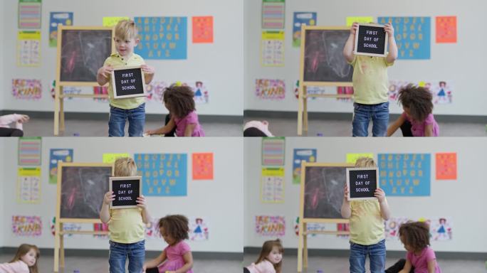 笨孩子在教室里举着开学第一天的牌子