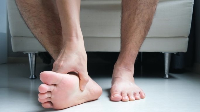 男人，脚底筋膜炎引起的脚部疼痛和腿部和脚踝抽筋，他用脚底来缓解疼痛。