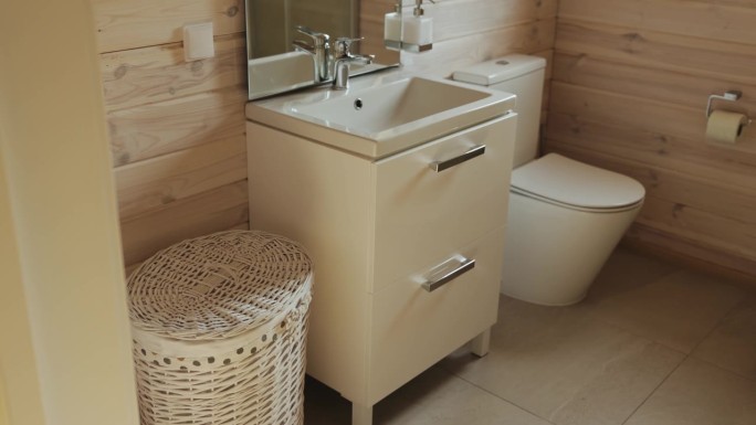 水槽，马桶，镜子在空荡荡的小浴室，木墙和柳条篮子脏衣服慢动作。