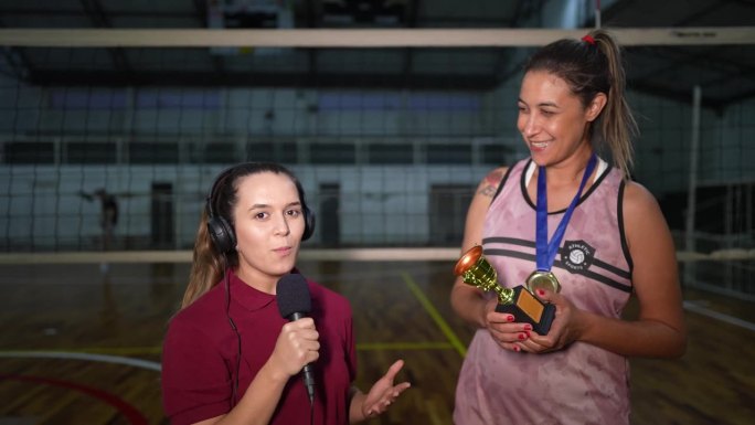 年轻女电视记者在体育场上采访赢得比赛后的女排运动员——镜头的视角