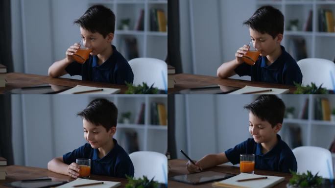 小男孩一边学习一边喝橙汁