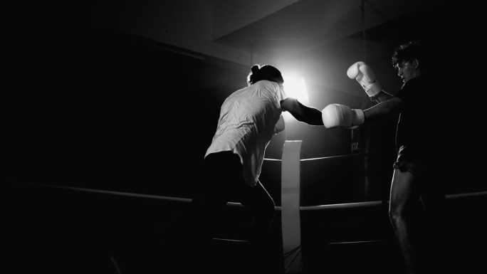 拳手猛击对手，对手闪避出拳，拳台内的拳手们在激烈的黑白、单色镜头中