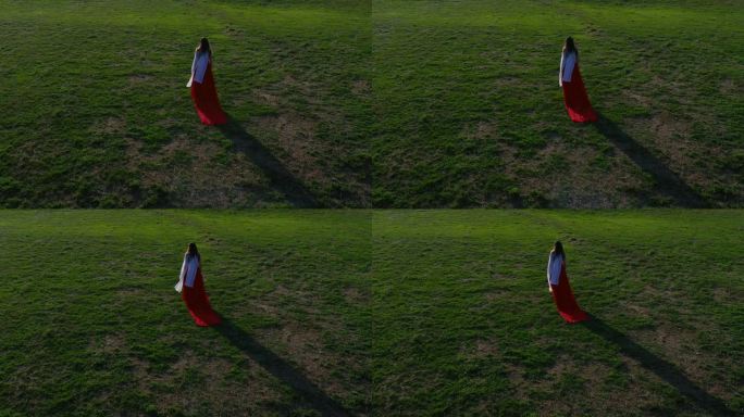 身穿红色长裙、戴白色围巾的女子走过草地