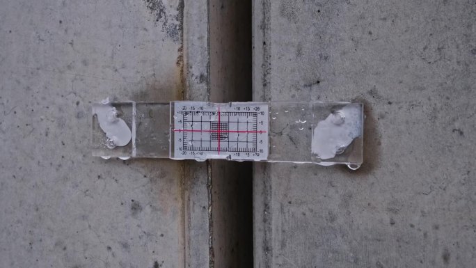 结构裂缝监测装置，带标准指示计和刻度，用于测量固定在两块混凝土墙板上的位移
