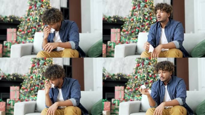 一个患有过敏症的年轻人在冬季新年圣诞假期坐在家里客厅的沙发上打喷嚏。